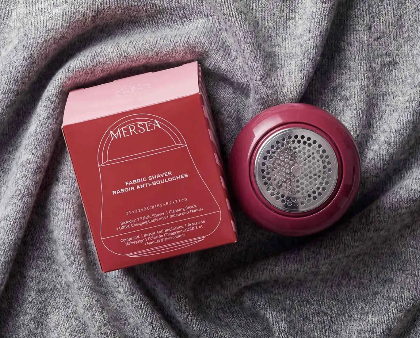 Red MERSEA fabric shaver beside its packaging on gray fabric